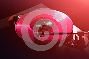 Vinyl DJ turntable in club lighting. close-up. pink tint. retro style