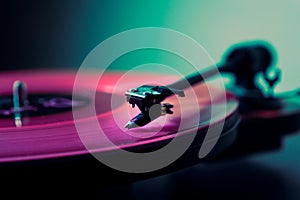 Vinyl DJ turntable in club lighting. close-up. pink tint. retro style