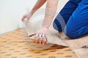 vinyl floor installation. Close-up hands of worker at home flooring renovation.