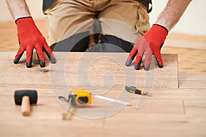 vinyl floor installation. Close-up hands of worker at home flooring renovation.