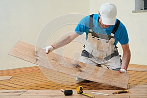 vinyl floor installation. Close-up hands of worker at home flooring renovation.