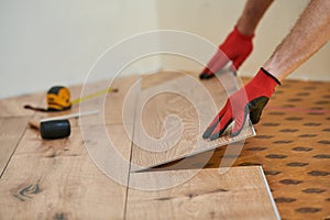 vinyl floor installation. Close-up hands of worker at home flooring renovation.