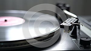 The vinyl record on DJ turntable record player close up. The rotating plate and stylus with the needle close-up neutral