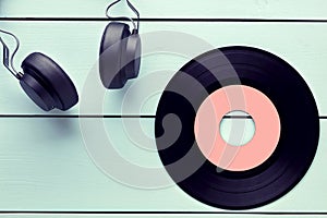 Vinyl record and a headphone on blue wooden background