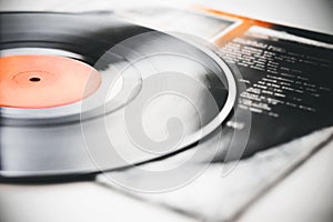 A vinyl record lies on the paper cover of the music album