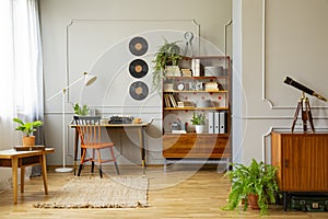 Vinyl records decorations on a gray wall with molding and wooden furniture in a retro home office interior for a writer. Real phot