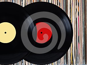 Vinyl records in front of pile of many close standing vinyl disks in old color covers over black background