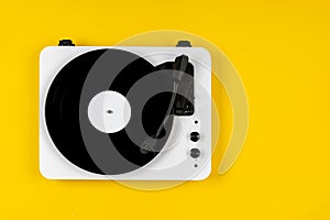 Vinyl turntable with vinyl plate on a yellow background. Modern gramophone record player. Retro sound technology to play music