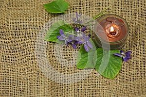 Viola flowers on the sackcloth with candle and copy space