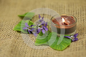 Viola flowers on the sackcloth with candle and copy space