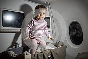 Violation of safety rules in an airplane. danger. cute little toddler jumping in baby bassinet during the flight