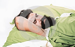 Violations of sleep and wakefulness. Young man sleeping on soft pillows in bed at home. Man bearded hipster having