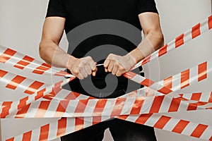 Violator breaks the signal tape with his hands. Protesting man breaks the protective tape on a white background.