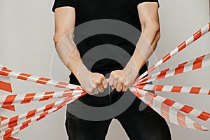 Violator breaks the signal tape with his hands. Protesting man breaks the protective tape on a white background.