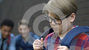 Violent multiracial schoolboys laughing at classmate in eyeglasses, humiliation