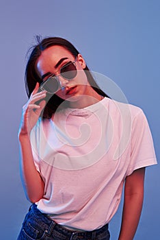 Violet background. Studio shot indoors with neon light. Portrait of beautiful young girl