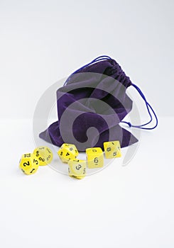 Violet bag, or pouch full of dices. Dices for rpg, board games, tabletop games or dungeons and dragons.