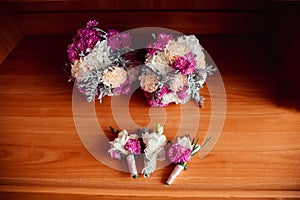 Violet and beige bouquets lie before boutonnieres