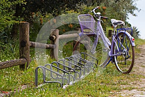 Violet bike with basket and bicycle racks near wooden fence