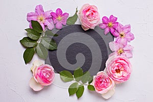 Violet clematis and pink roses flowers and empty slate board