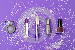 Violet cosmetics on an ultra violet background with sequins in o