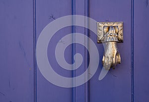 Violet door with a knocker hand