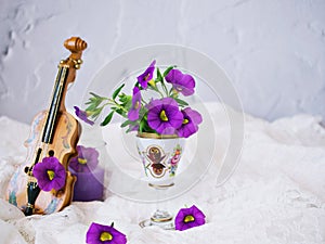 Violet flowers with violin toy on white embroidered cloth for background,Calibrachoa petunia Million bells ,Trailing petunia ,Supe