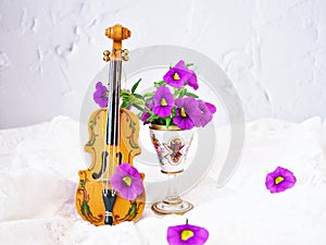 Violet flowers with violin toy on white embroidered cloth for background,Calibrachoa petunia Million bells ,Trailing petunia ,Supe