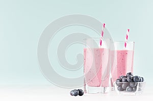 Violet fresh milk dessert with blueberries in bowl, striped straw in modern youth interior in pastel soft mint color and white.