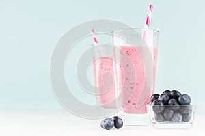 Violet fresh milk dessert with blueberries in bowl, striped straw in modern youth interior in pastel soft mint color and white.