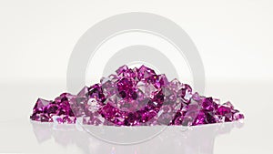 Violet jewel stones heap turning over white background