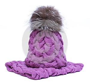 Violet knitted woolen scarf and hat with pompom isolated on white background.