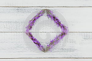 Violet liatris flowers wreath on white wood background