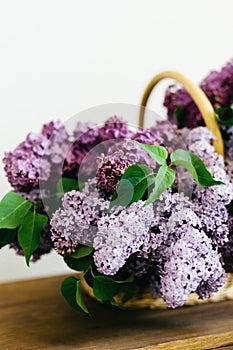 Violet lilac flowers bunch in a basket on wooden table