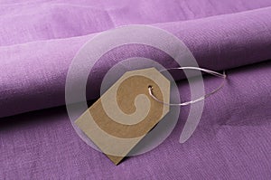 Violet linen fabric and blank price tag on it.Concept of fabric store and price points