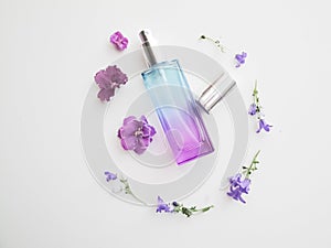 Violet perfume bottle with flowers around. lavender and spring flower aroma, aromatherapy, spa concept, skin care