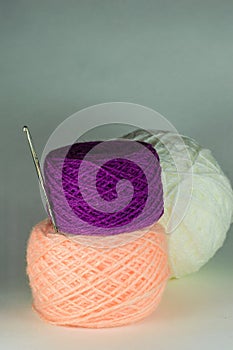 Violet and pink balls of yarn and a crochet hook.