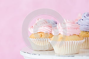 Violet and pink cupcakeson shabby shic stand on pink pastel background.