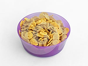 Violet plastic round medium size bowl for loose products filled with cornflakes isolated on a white background