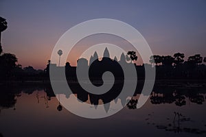 Violet sunrise over famous angkor wat temple with lake and reflection in the water with lillypad