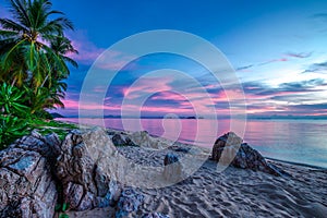 Violet sunset over the sea and rocky beach