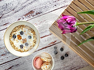 Violet tulip on wooden box and top view to bowl with cereals and capcakes