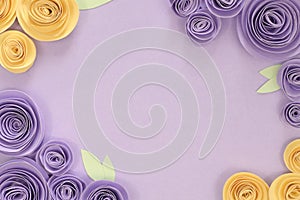Violet and yellow paper craft rose flower flat lay background with flowers and leaves on around the border