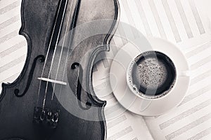 Violin acoustic classical instrument and white coffee cup on sheet for musical notes