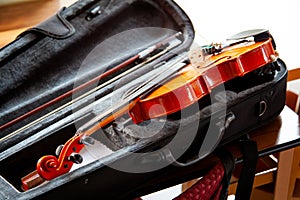 Violin with a bow laying in an open black fiddle case on the table. Classical musical string instruments group concept, nobody