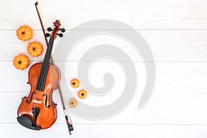 Violin, bow and pumkin on white wood background. Autumn flatlay wit copyspace