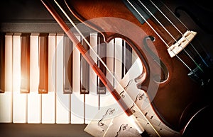 Violin bow and sheet music on piano keys top