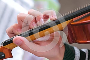 Violin in boy`s hands. Boy is learning to play violin. Correct setting of the fingers of the left hand on the strings of