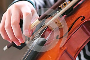 Violin in boy`s hands. Boy is learning to play violin. Correct setting of the fingers of the right hand on the strings