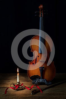 Violin and Burning Candle in Dark Room